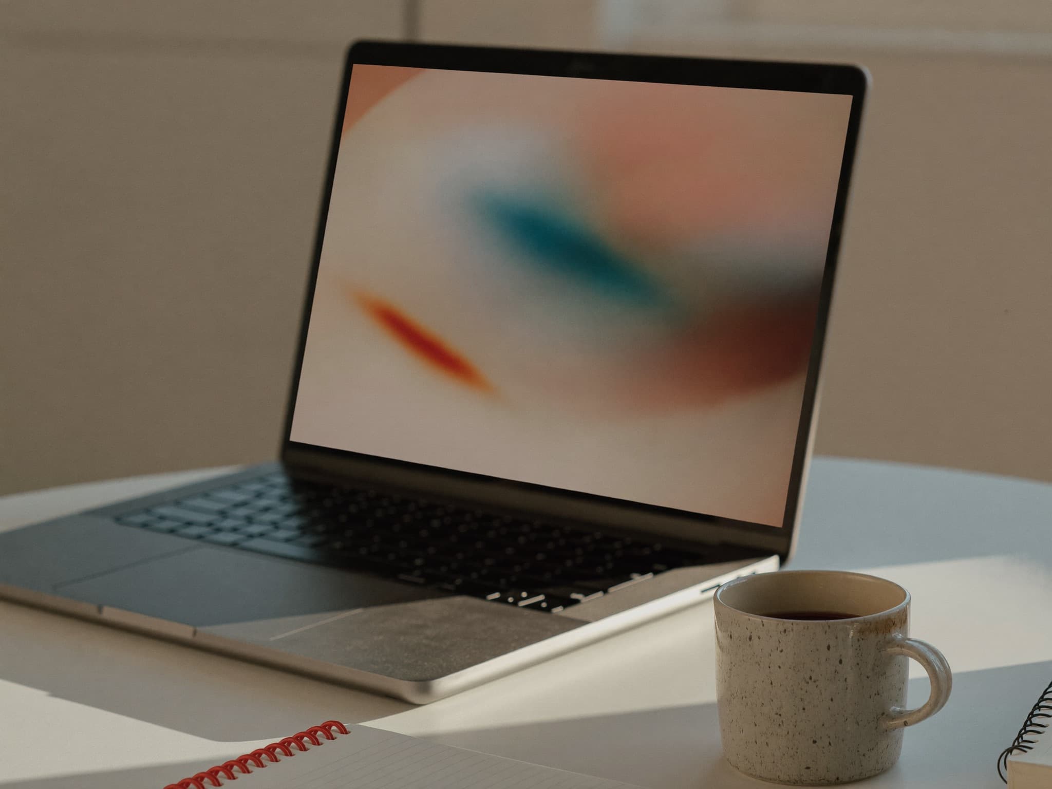 An open laptop on a minimal desk beside a coffee cup